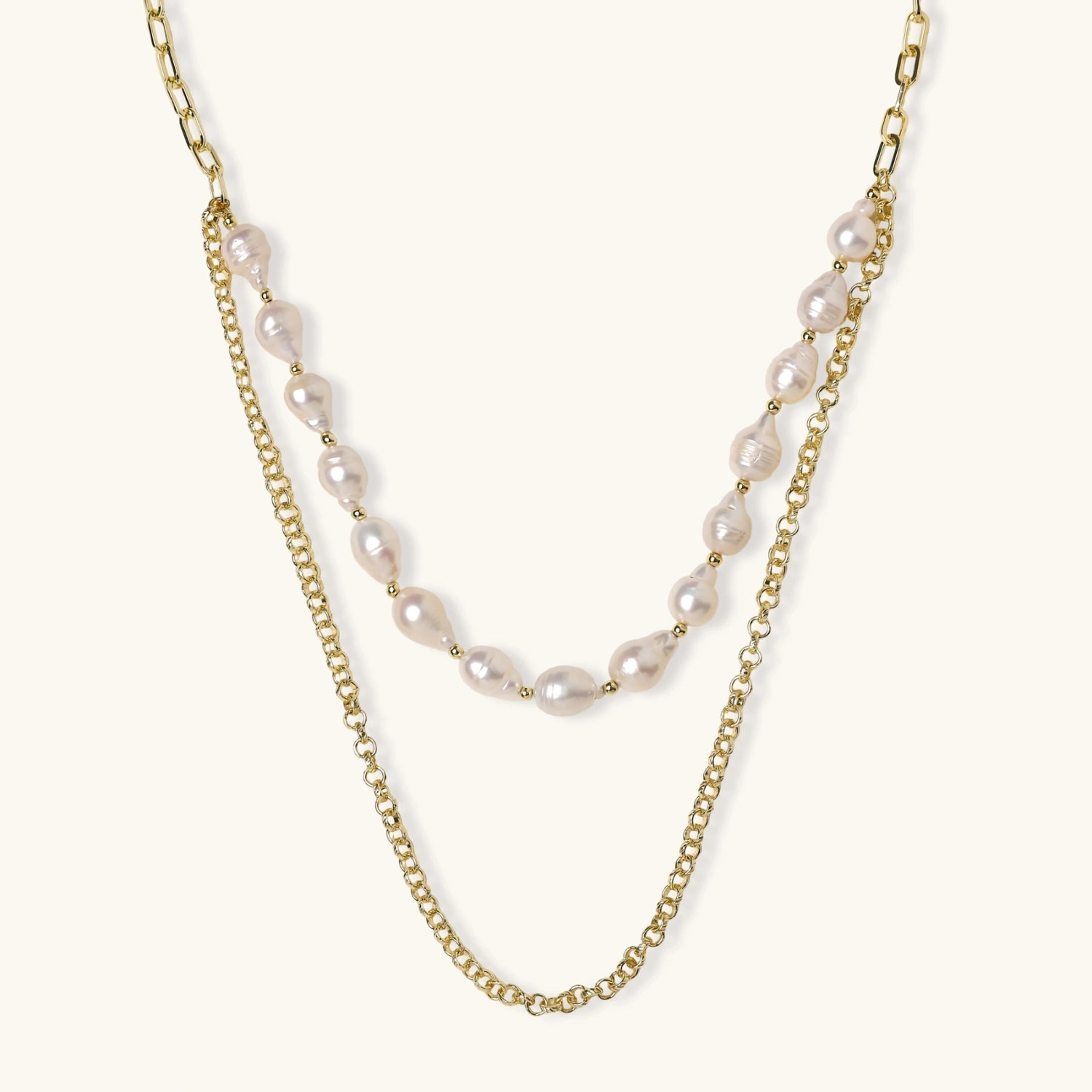 Layered gold chain necklace with organic baroque freshwater pearls and adjustable length on cream background