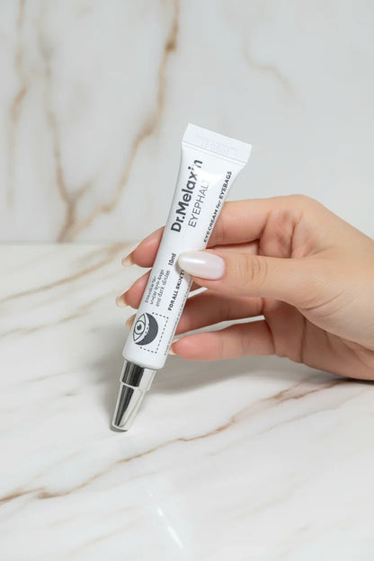 يد أنثوية تمسك كريم العين بأناقة