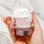 يد تمسك كريم الكولاجين على رخام أبيض وذهبي