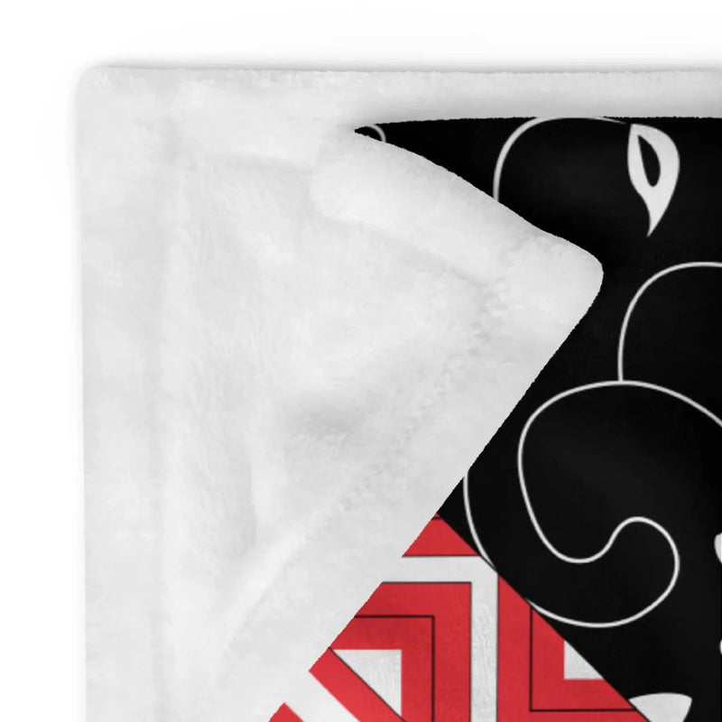 Ivorynn plush throw blanket with black floral and red geometric patterns, white backing