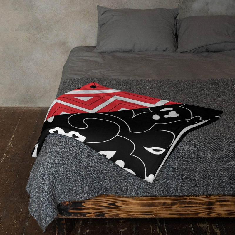 Modern bed with gray bedding and a floral throw blanket featuring red, black, and white patterns