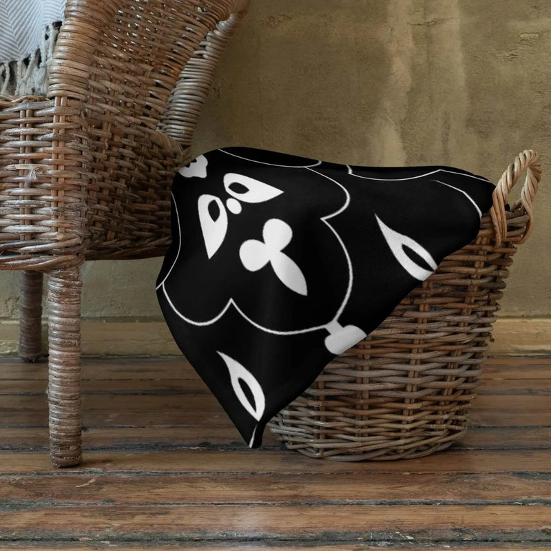 Black and white floral throw blanket draped over wicker basket on wooden floor, Ivorynn home decor