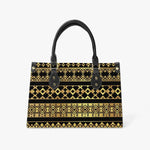 Geometric gold and black tote bag with black handles, modern fashion accessory on white background