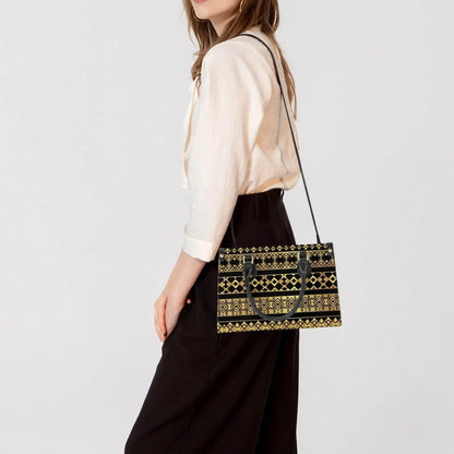 Woman wearing modern ivory blouse and black pants, carrying a black and gold patterned tote bag with long strap from Ivorynn fashion collection.