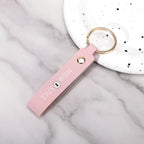 Pink leather keychain with gold ring and 'MISHA STYLE' text, on marble surface near white speckled dish
