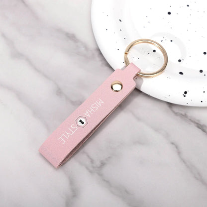 Pink leather keychain with gold ring and 'MISHA STYLE' text, on marble surface near white speckled dish