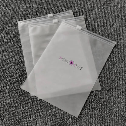 Three clear MISHA STYLE zipper bags on textured gray carpet