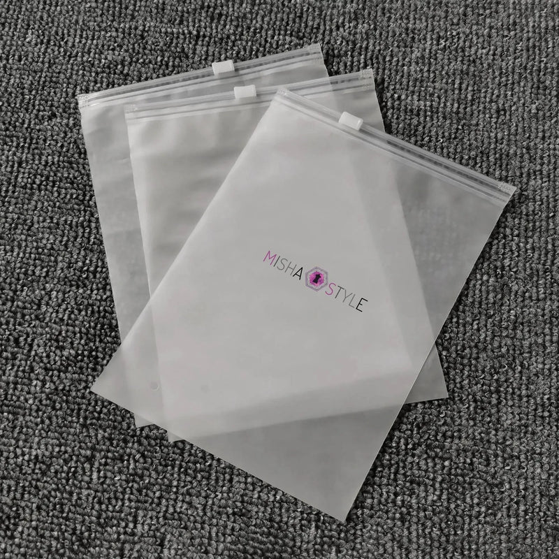 Three clear MISHA STYLE zipper bags on textured gray carpet