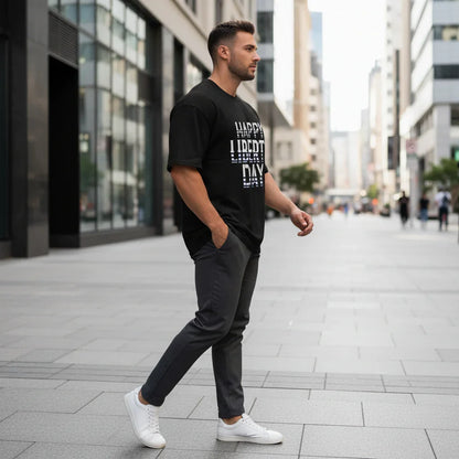 Athletic man in black graphic t-shirt, gray pants, and white sneakers walking in city street