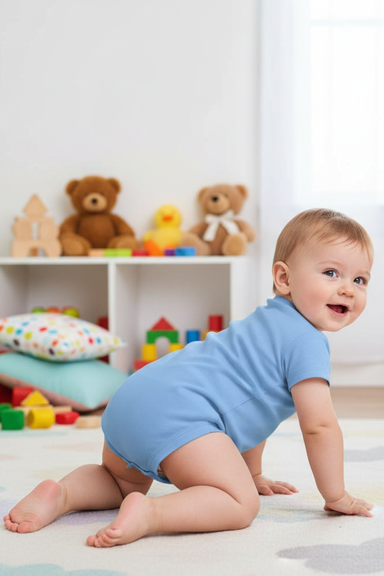 Baby boy in blue onesie - back view in children's room