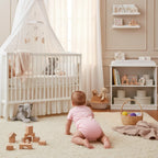 Baby boy in pink onesie - back view in nursery