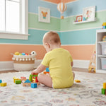 Baby boy in yellow onesie - playing back view