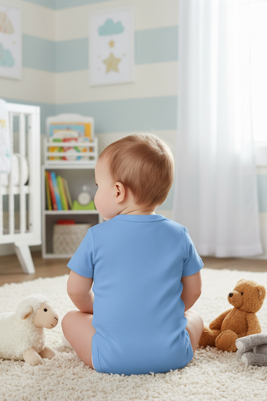 Baby girl in blue onesie - back view in children's room