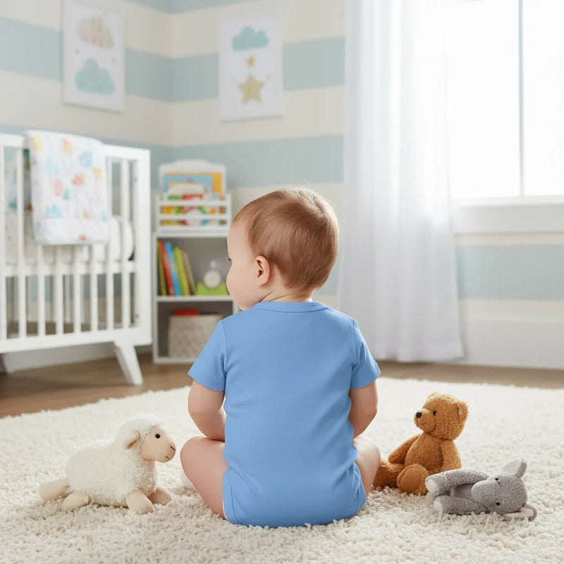 Baby girl in blue onesie - back view in children's room