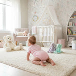 Baby girl in pink onesie - back view in nursery