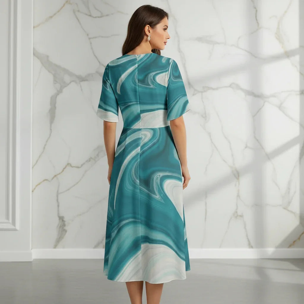 Back view of woman in teal and white swirl print midi dress, marble wall background, Ivorynn fashion