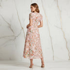 Back view of woman in pink floral dress and heels in a modern marble setting, Ivorynn fashion
