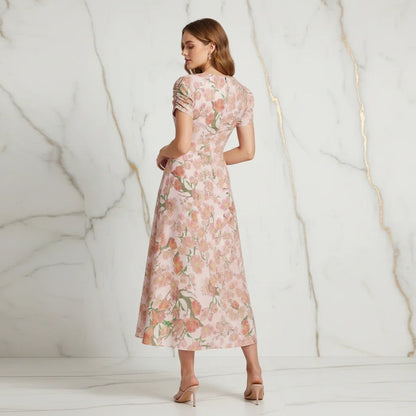 Back view of woman in pink floral dress and heels in a modern marble setting, Ivorynn fashion
