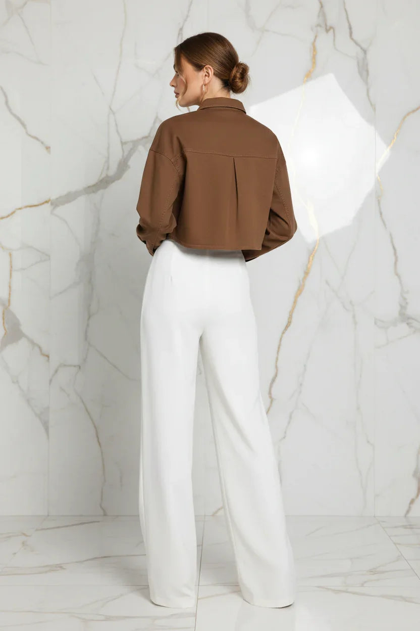 Back view of brown denim shirt with white pants on marble background
