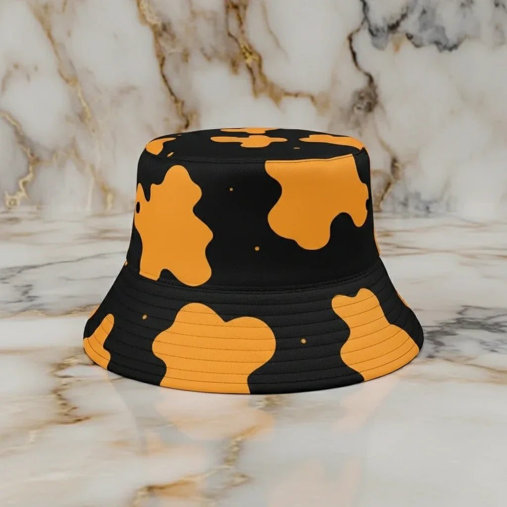 Black bucket hat with bold orange abstract print on marble surface at Ivorynn