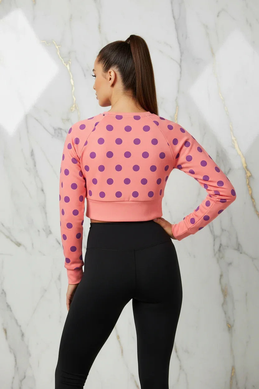 Back view of woman in pink polka dot crop top and black leggings, stylish activewear by Ivorynn