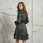 Woman in stylish black printed dress with ruffle hem, posing in front of marble wall at Ivorynn