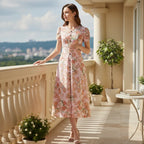 Woman in floral summer dress standing on balcony with city view, stylish apparel by Ivorynn