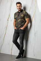 Man wearing camo print polo shirt, black jeans, and sneakers, posing against marble wall