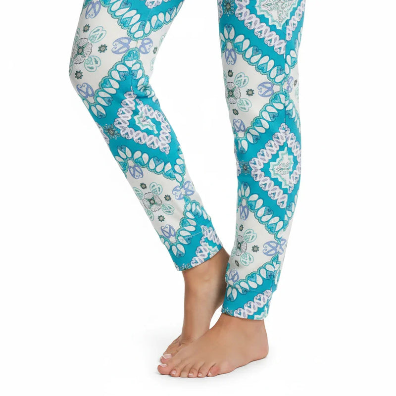 Woman's lower legs in blue and white patterned leggings from Ivorynn, barefoot on white background.