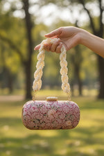 Close-up of woman's hand holding pink clutch