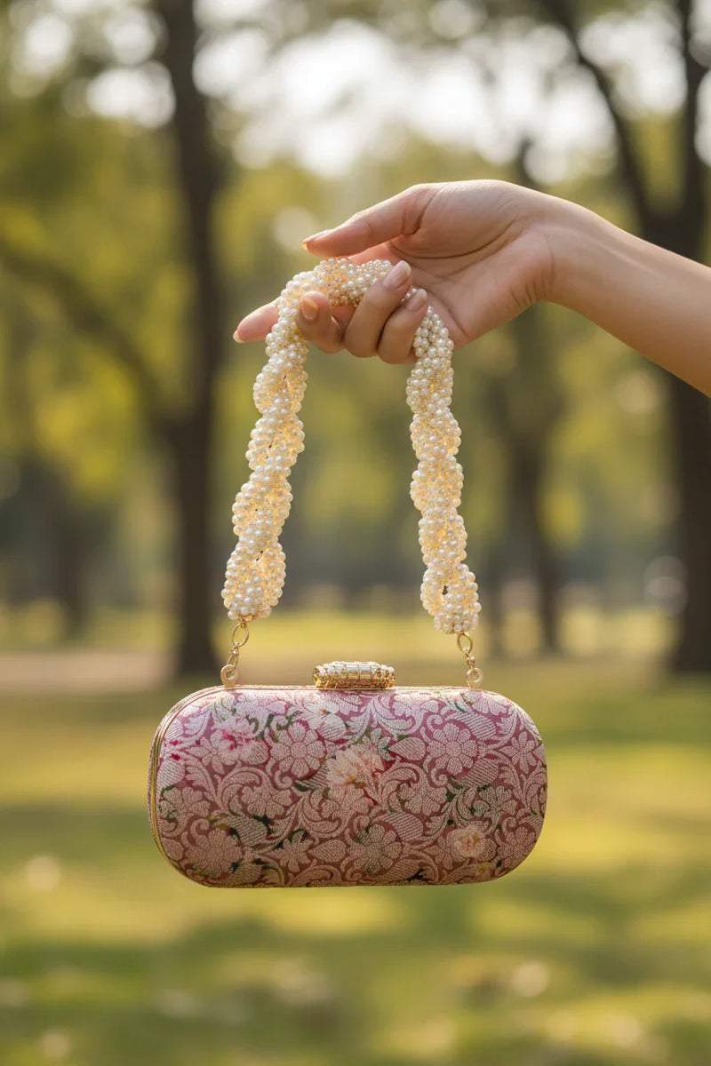 Close-up of woman's hand holding pink clutch