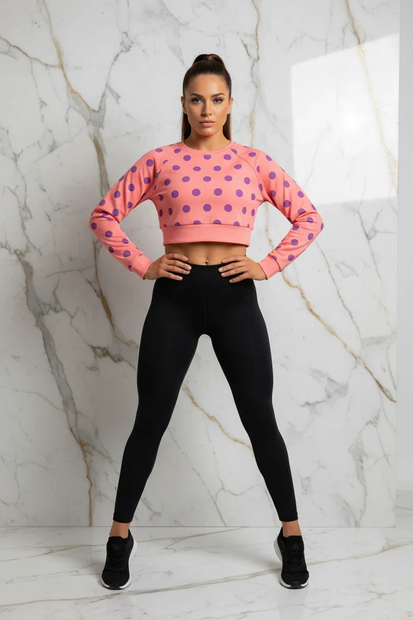 Woman in pink polka dot crop top and black leggings posing confidently, Ivorynn fashion apparel