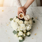Couple's hands with ring box and white rose bouquet on marble, wedding at Ivorynn