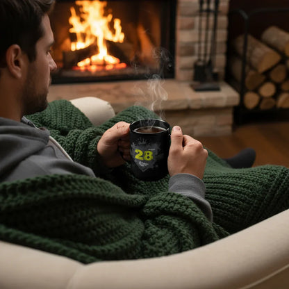 Man relaxing by fireplace holding a steaming black mug, cozy in green knit blanket, Ivorynn style