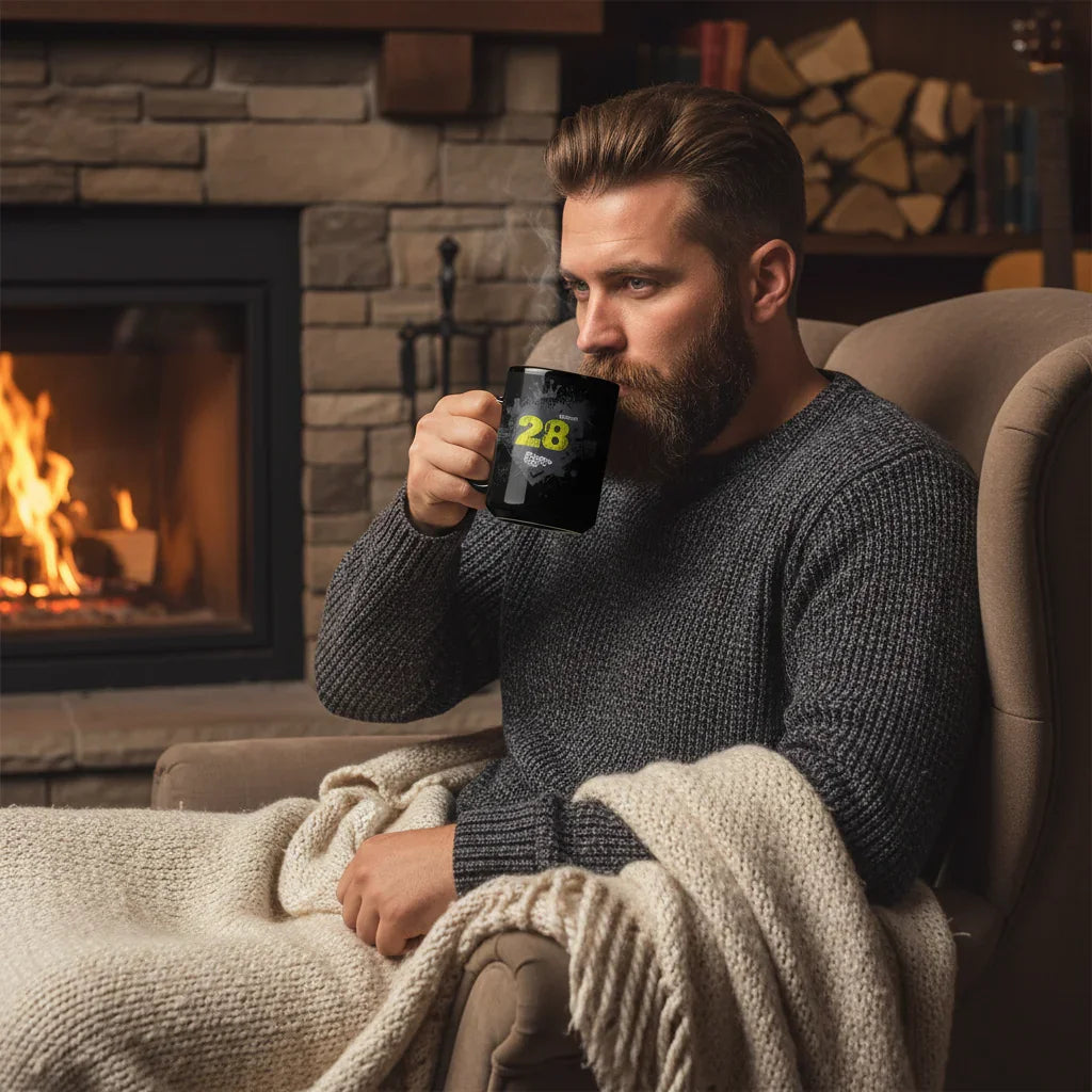 Man in grey sweater drinking from black dubstep mug by fireplace, cozy winter scene