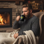 Man in grey sweater drinking from black dubstep mug by fireplace, cozy winter scene