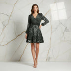 Woman in a long sleeve floral print dress standing against a white and gold marble wall, fashionable attire from Ivorynn.