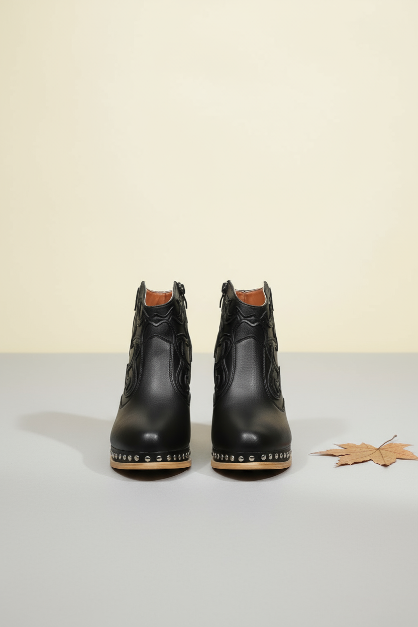 Black cowboy boots with studded details on a white background