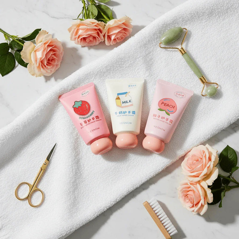 Fruit Fragrance Milky Hand Cream tubes in pink packaging with floral accents on a white towel background.
