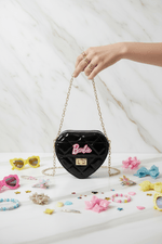 Hand holding chain black bag with kids accessories