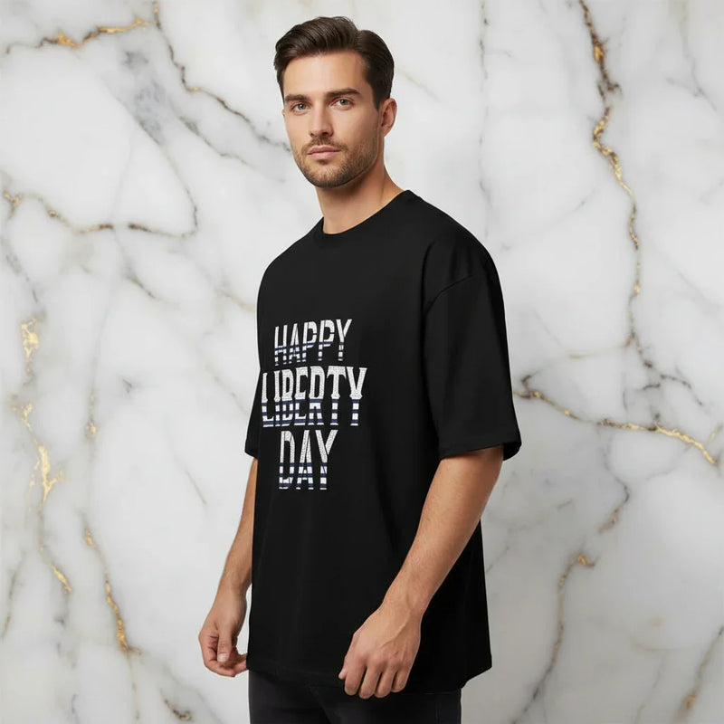 Man wearing black 'Happy Liberty Day' graphic t-shirt from Ivorynn, marble background