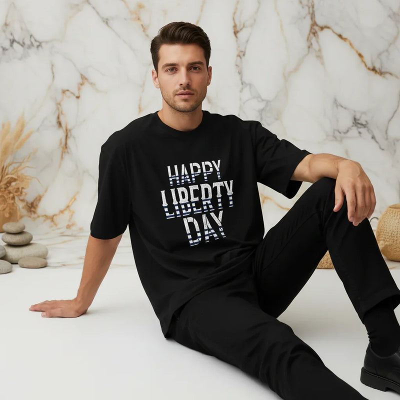 Man seated in modern marble room wearing black 'Happy Liberty Day' t-shirt from Ivorynn