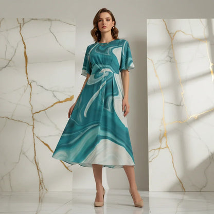 Woman in a teal marble-pattern midi dress standing against marble panels, stylish fashion at Ivorynn