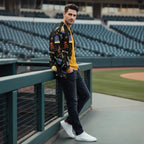 Stylish man in graphic black jacket, yellow sweater, and white shoes at stadium, Ivorynn fashion