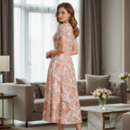 Woman in floral pink midi dress standing in a modern living room, Ivorynn fashion