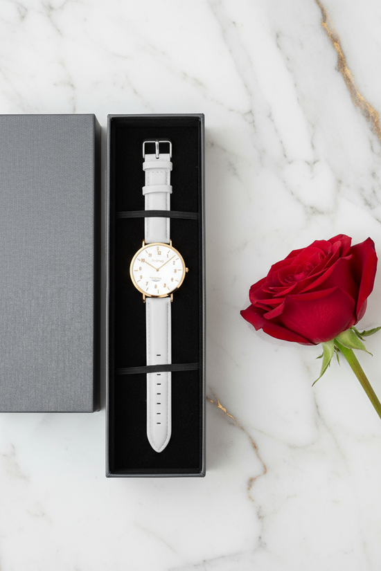 Overhead view of watch in box with red rose