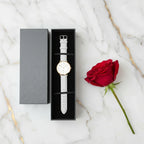 Overhead view of watch in box with red rose