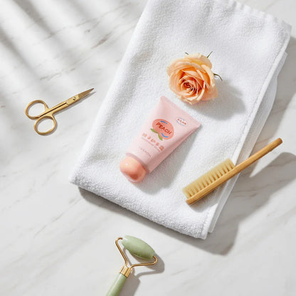 Fruit Fragrance Milky Hand Cream on a white towel surrounded by a flower, scissors, a comb, and a jade roller.