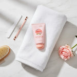 Fruit Fragrance Milky Hand Cream with peach scent on a white towel with a rose and manicure tools.