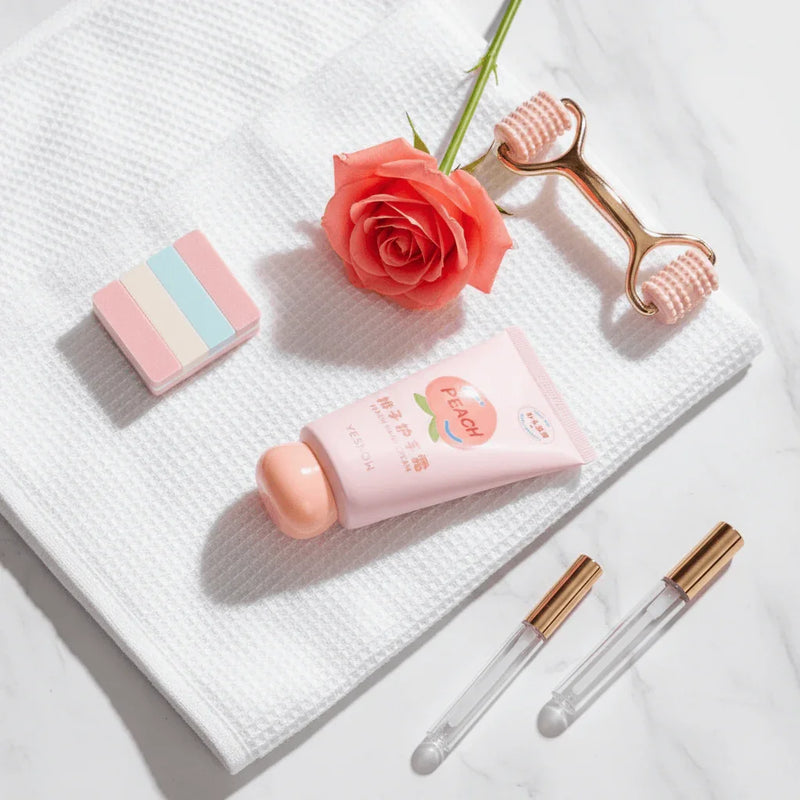 Fruit Fragrance Milky Hand Cream on a towel with a rose, roller, and beauty tools, showcasing a skincare routine.